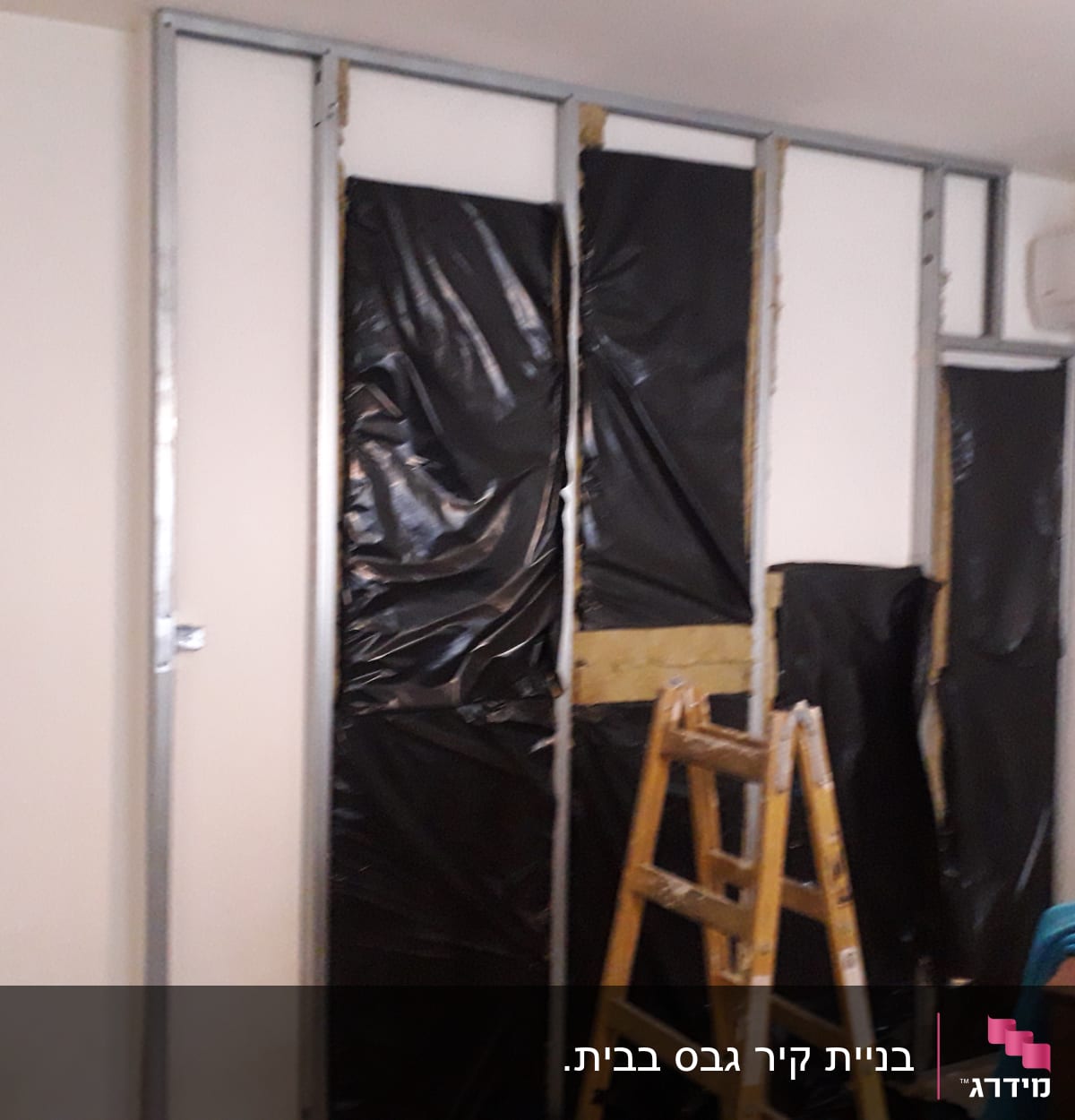 קיר גבס בבנייה עם מסגרת מתכת וסולם עץ